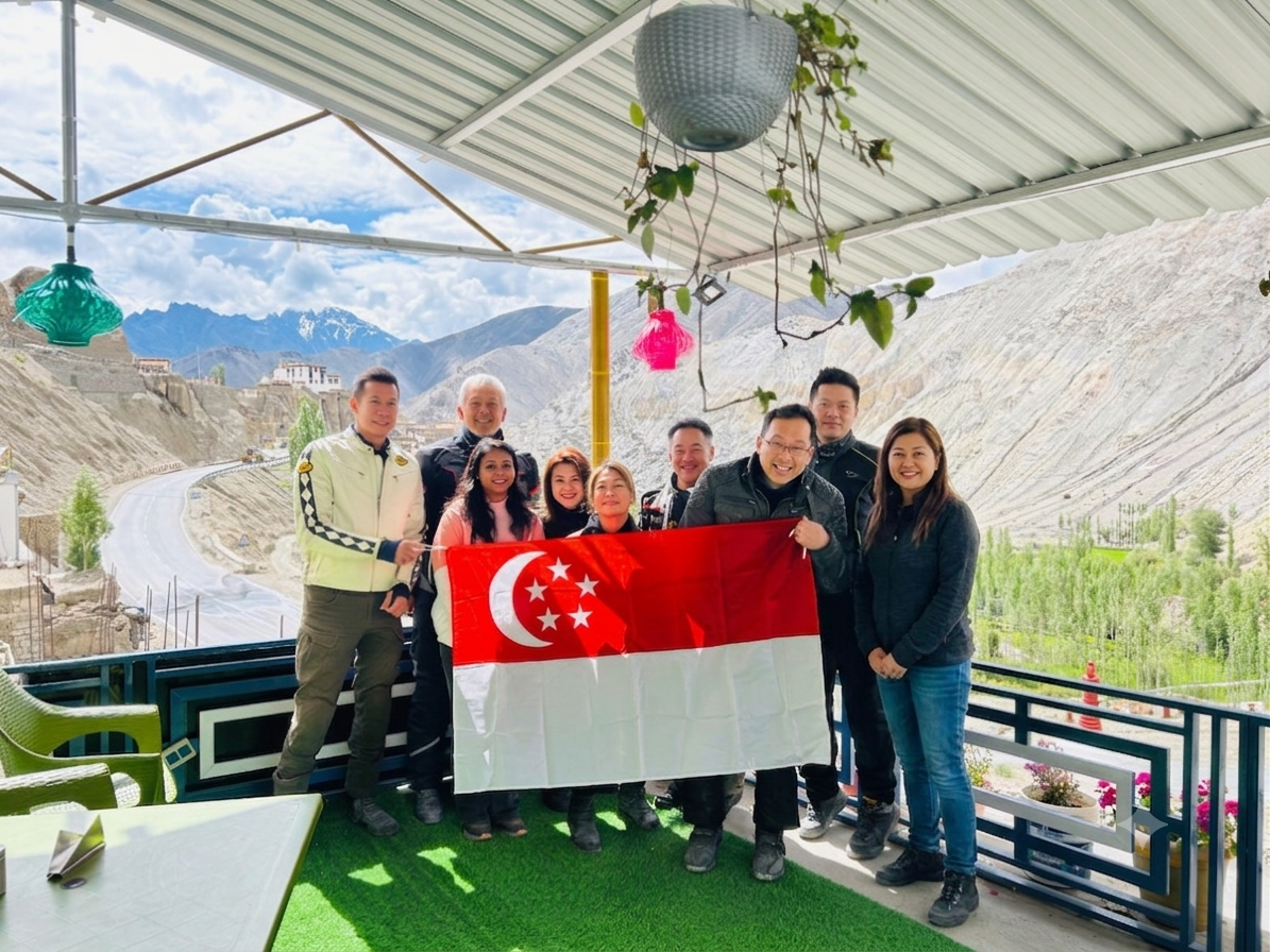 Group holding a flag on a terrace in the mountains